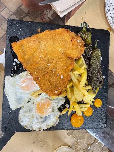 Filete empanado con huevos fritos, patatas y pimientos